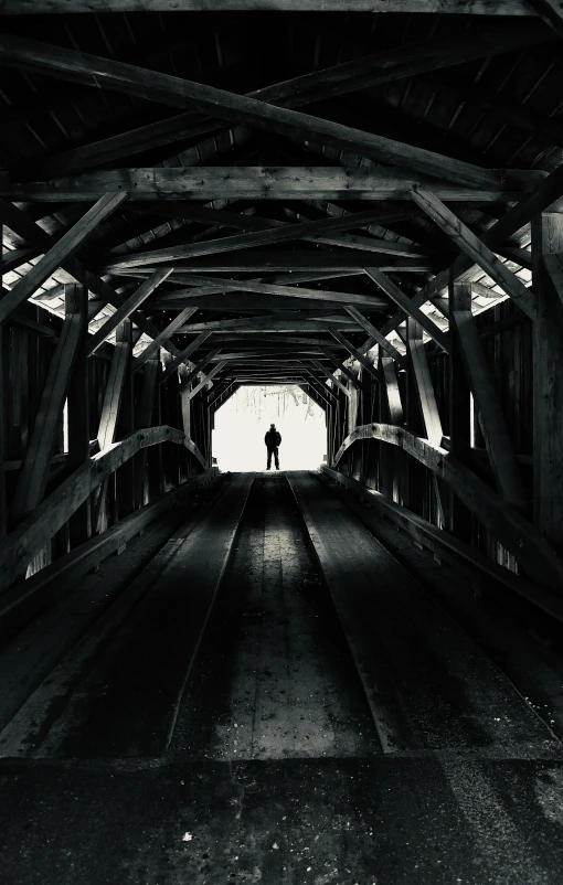 silhouette of man in black and white pograph walking through a tunnel