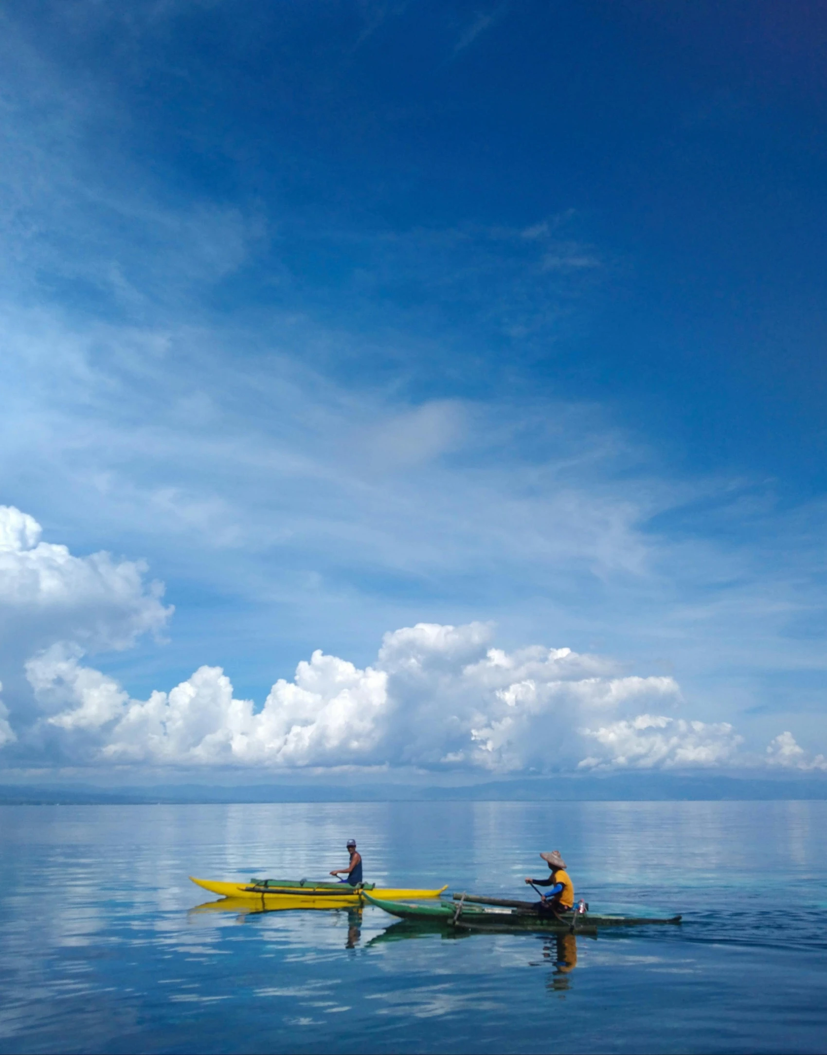 two kayakers sit side by side on clear water