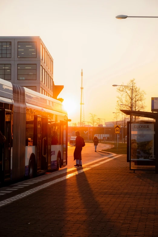 people are walking towards a city bus at sunset