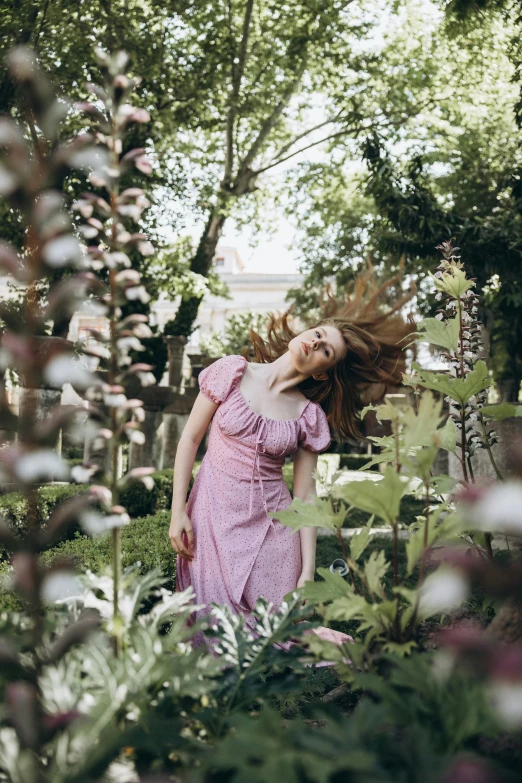 a woman standing under trees with long hair in her hand