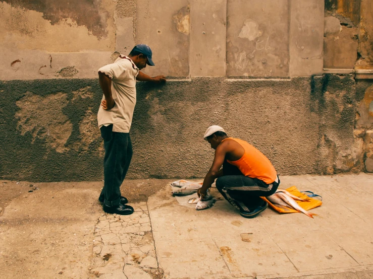 two men with their backs to one another, leaning against a wall