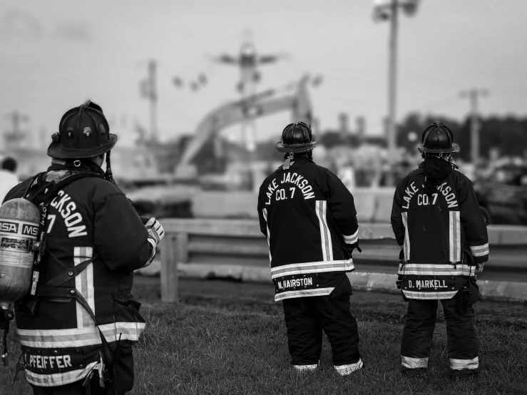 three firefighters are standing in line facing away from the camera