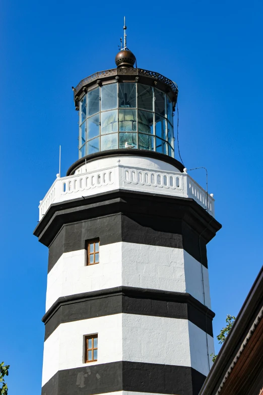 a white and black tower with windows and a sky background