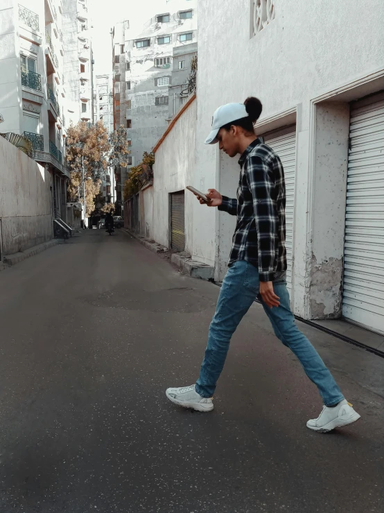 a boy on his phone walks down the street in an alley