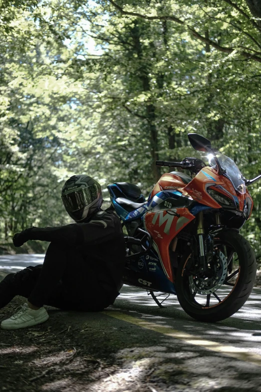 a person sits on the ground next to a motorcycle