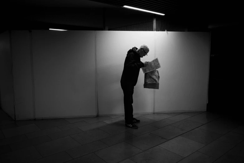 man leaning on wall with newspaper in hand