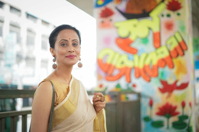 woman in yellow saree smiling in front of painting