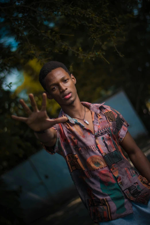 a man in an abstract shirt is holding up his hands