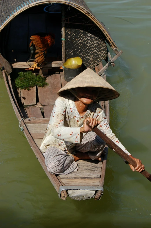 the person is sitting on the boat holding a stick