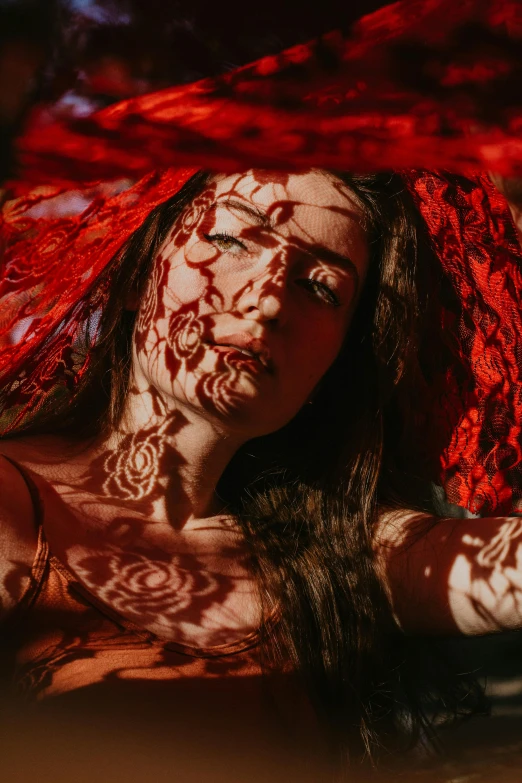 a woman wearing a red dress and intricate hendi is holding her hand up to her face