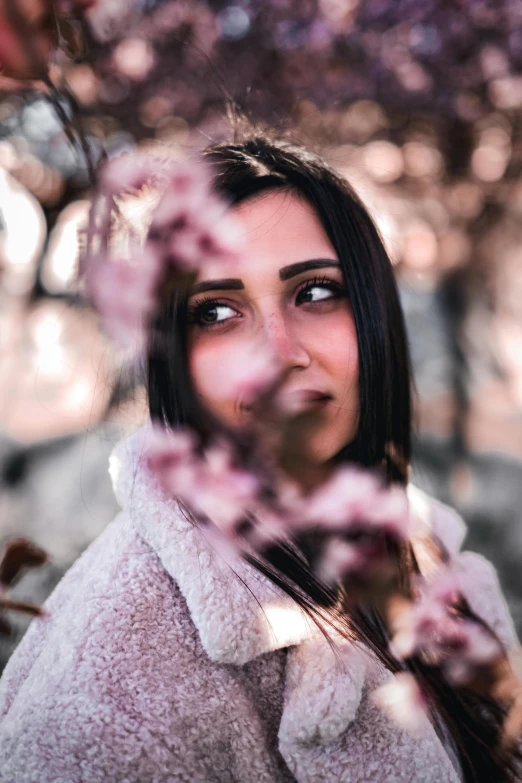 a woman standing behind some trees looking up