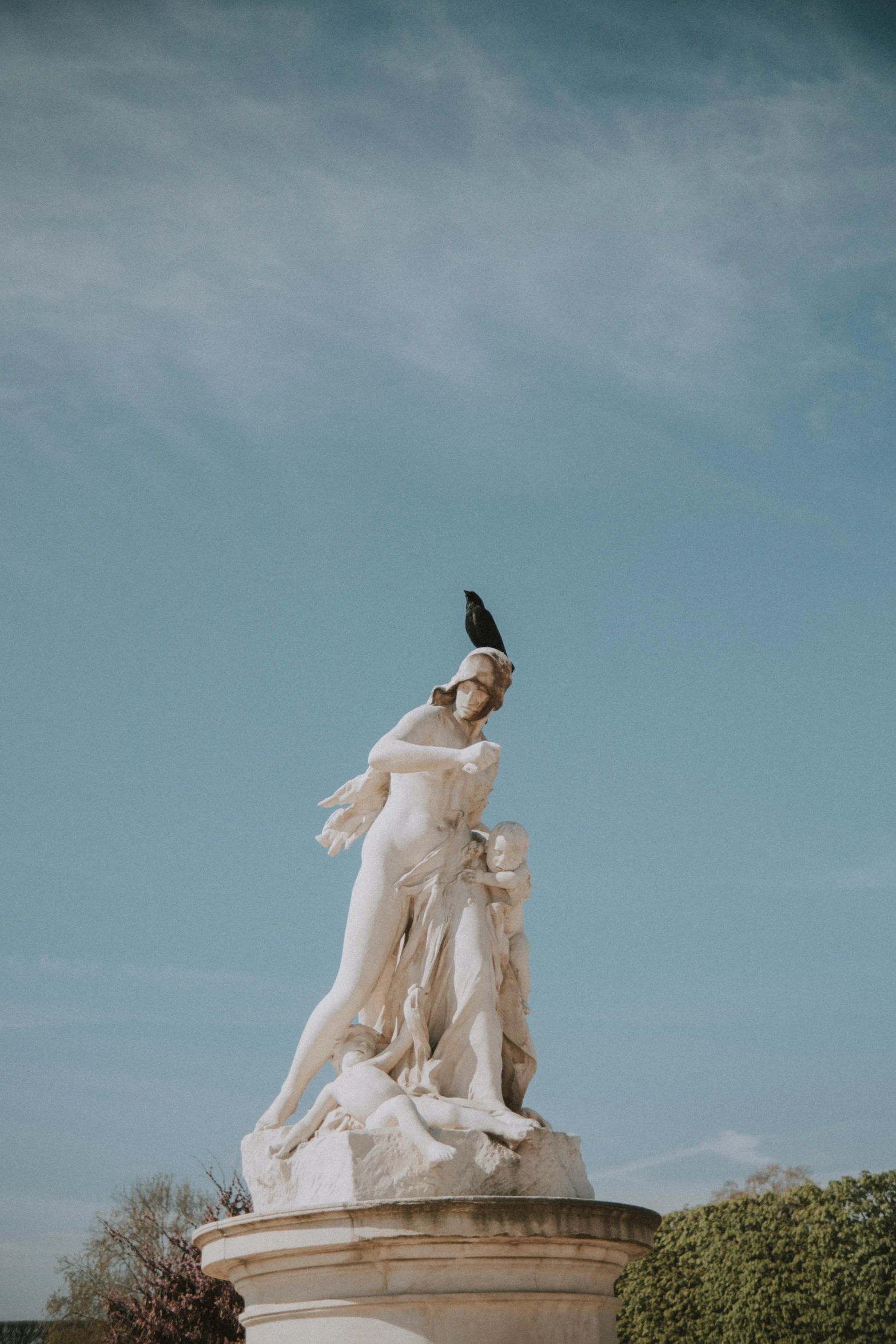 a statue sitting on top of a pedestal with trees