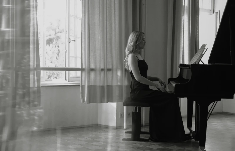 a woman sitting at a piano in front of a window