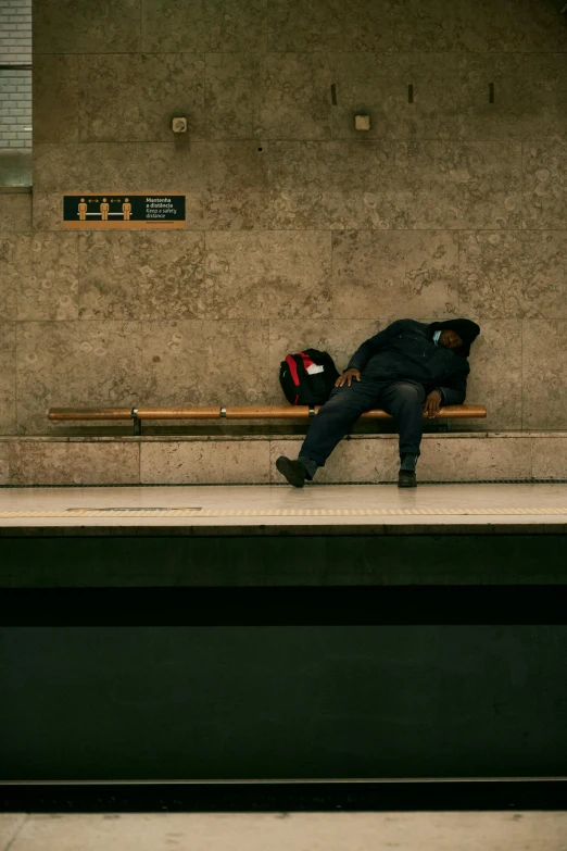 a man sleeps on a bench near an empty subway station