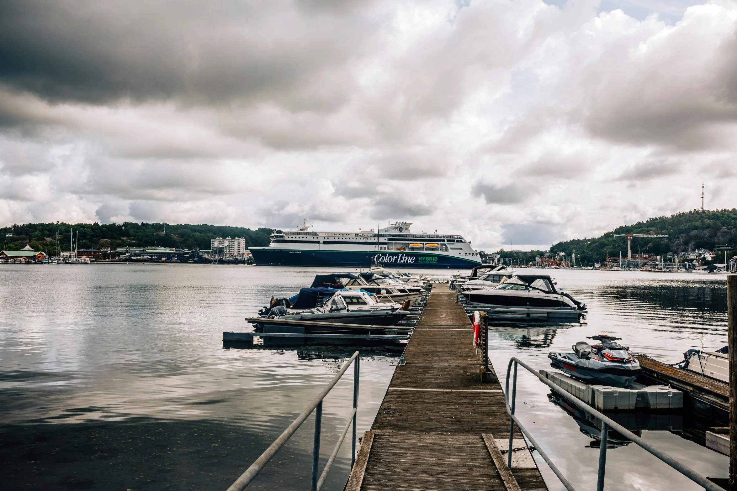 a dock next to the water and boats with a cruise ship in the background