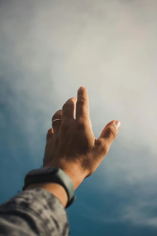 hand reaching up into the air to reach out to a blue sky