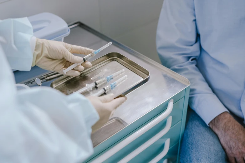 two people receiving injections in the middle of a hospital bed