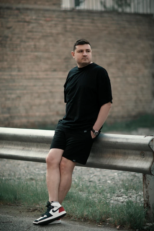 a person is posing on a fence in black shorts and sneakers