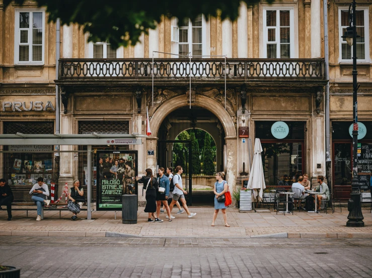 a group of people walking through a square next to a tall building