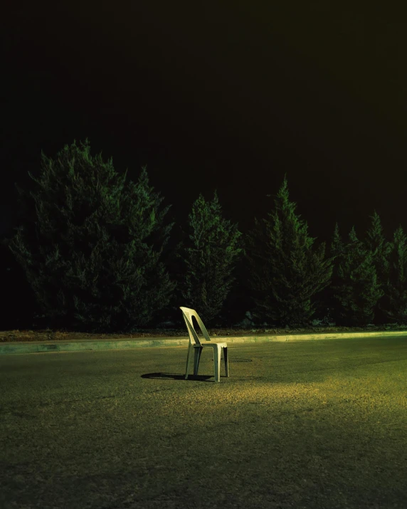 a white lawn chair on grass next to trees