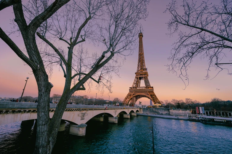 a bridge crossing a river below the eiffel tower