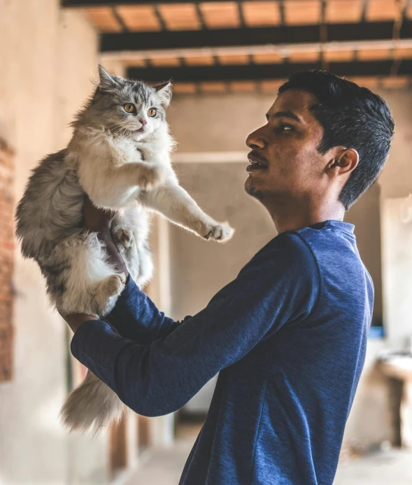 man holding a cat and posing for a picture