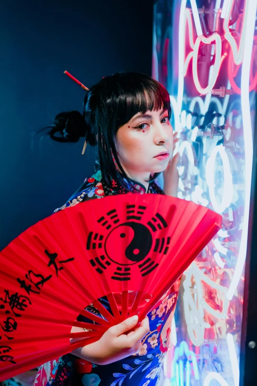 a girl standing in front of neon signs holding a red fan