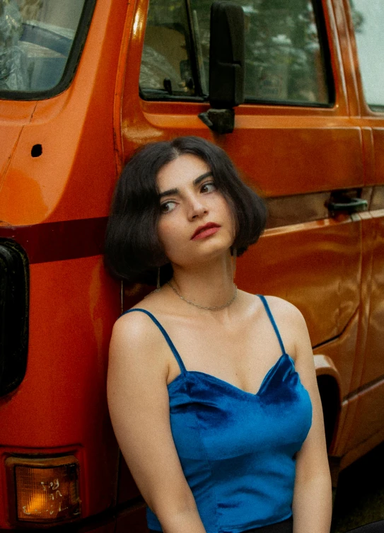 a beautiful young lady leaning against the side of a van