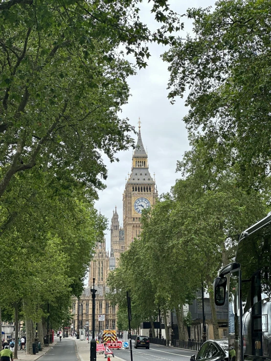 a city street lined with trees next to a big ben tower