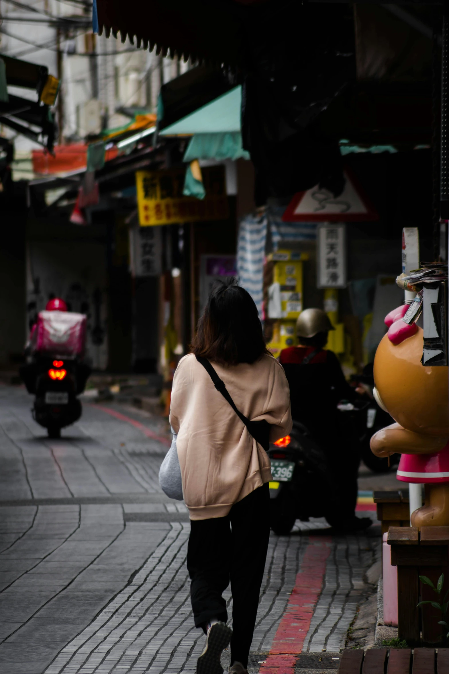 a woman walking down a sidewalk past stores