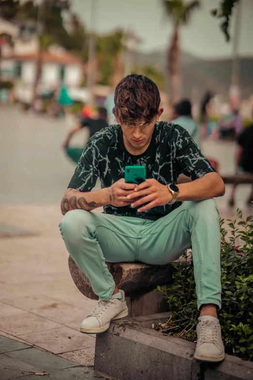 a young man sitting on top of a cement step with his phone