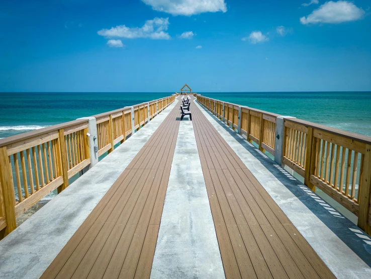 a bridge going to the ocean with benches