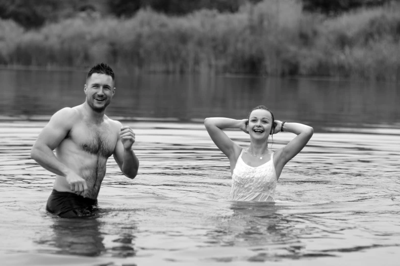 a man and woman walking through a body of water