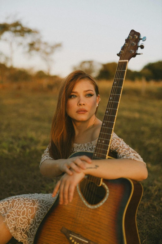 a woman is sitting down holding a guitar