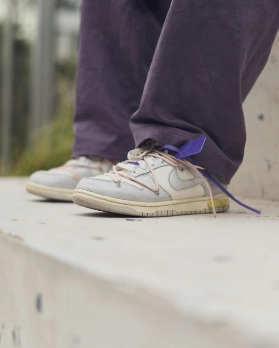 a person in a white and gray pair of shoes on top of a ledge