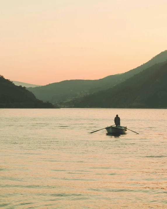 someone in a boat at sunset on the water