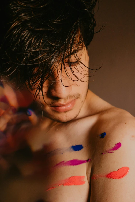 a shirtless man with his arm covered in colorful swatches