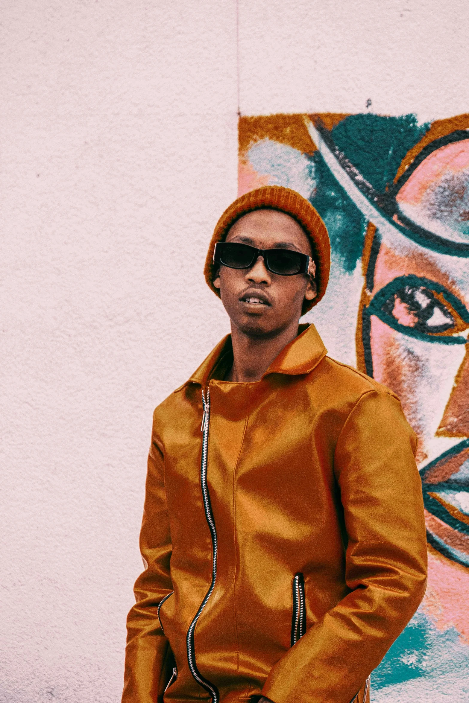 a man in a yellow jacket is standing next to graffiti