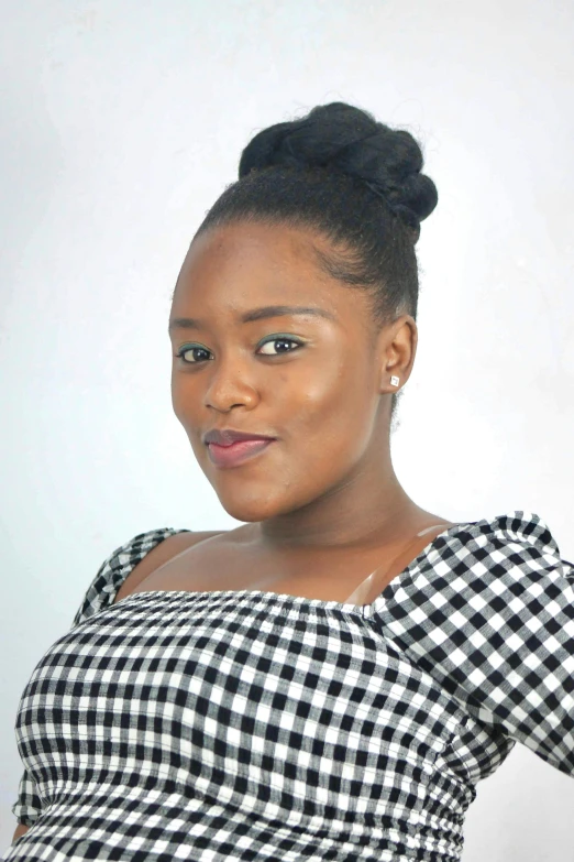 an african american woman poses for the camera in a black and white checkered top