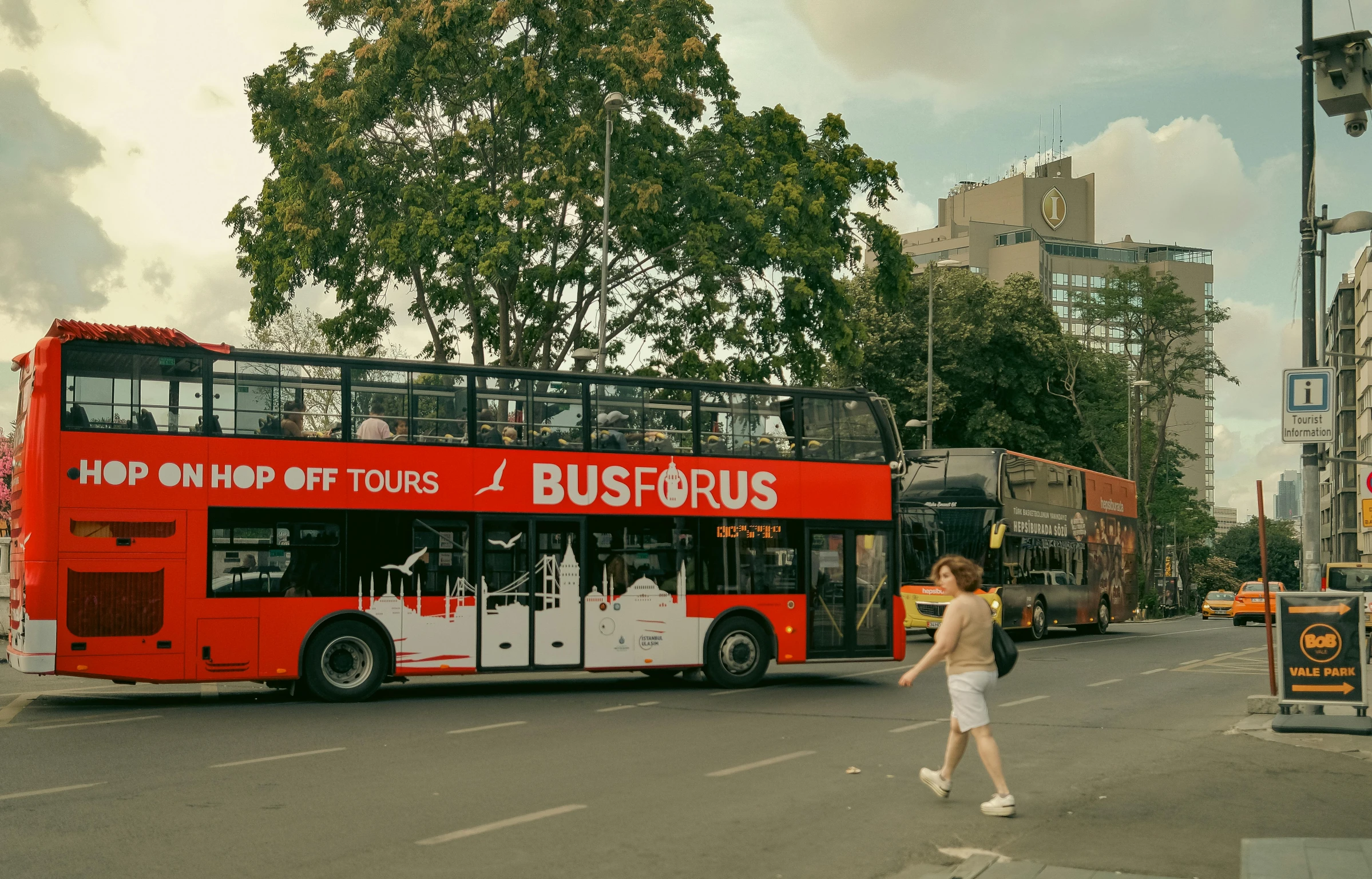 two people cross the road near some double decker buses