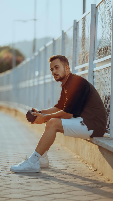 the man is posing for a po next to a fence