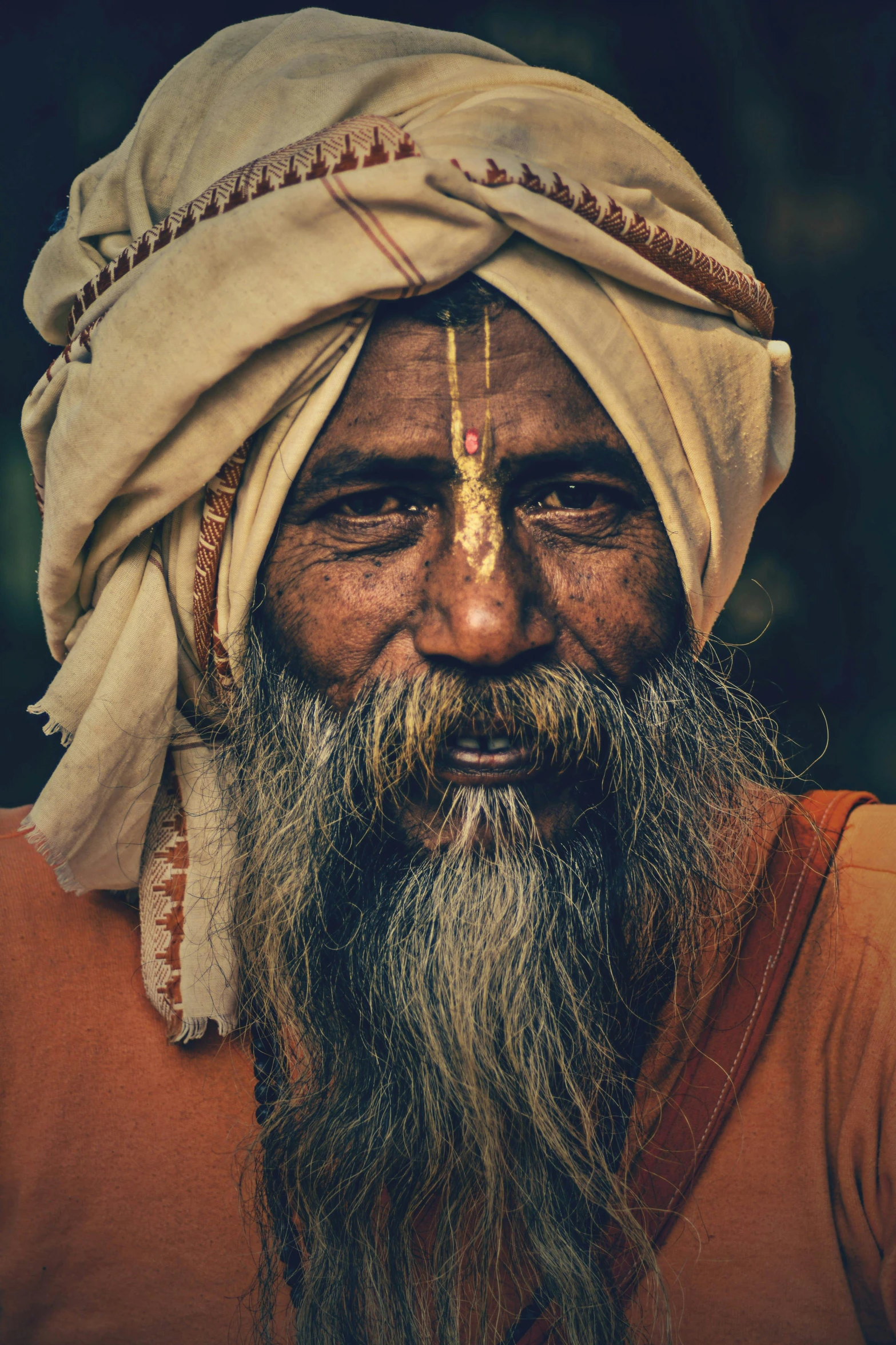 an old man with a beard wearing a turban and looking into the camera