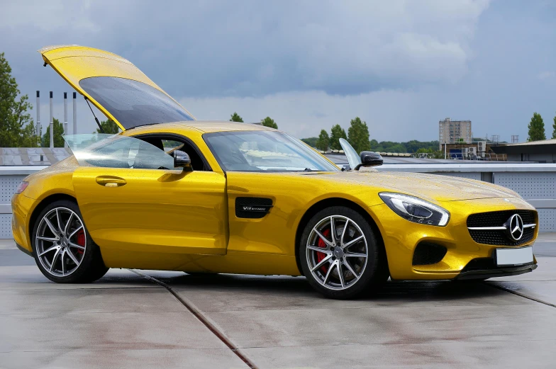 a bright yellow mercedes sls with its hood open