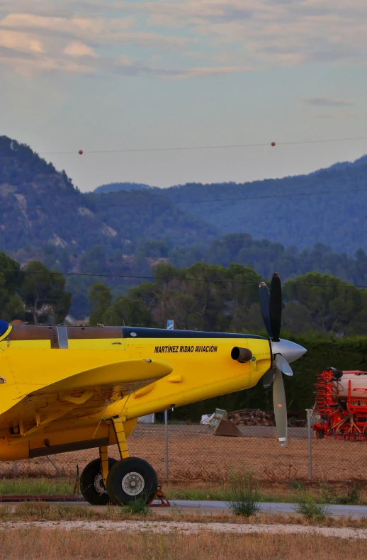 a small yellow airplane parked in the middle of an airfield
