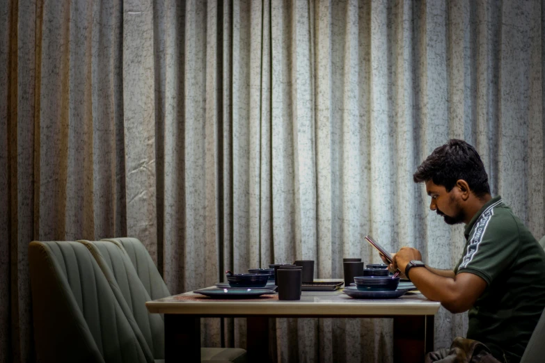 a man sitting at a table and texting on his phone