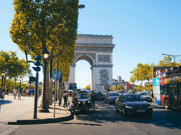 cars are driving down the road below the arch of triumph