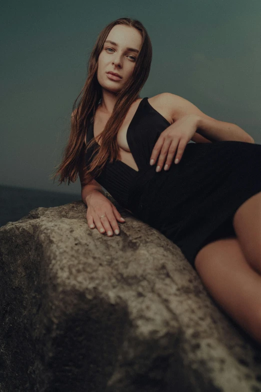 a woman is sitting on top of a large rock