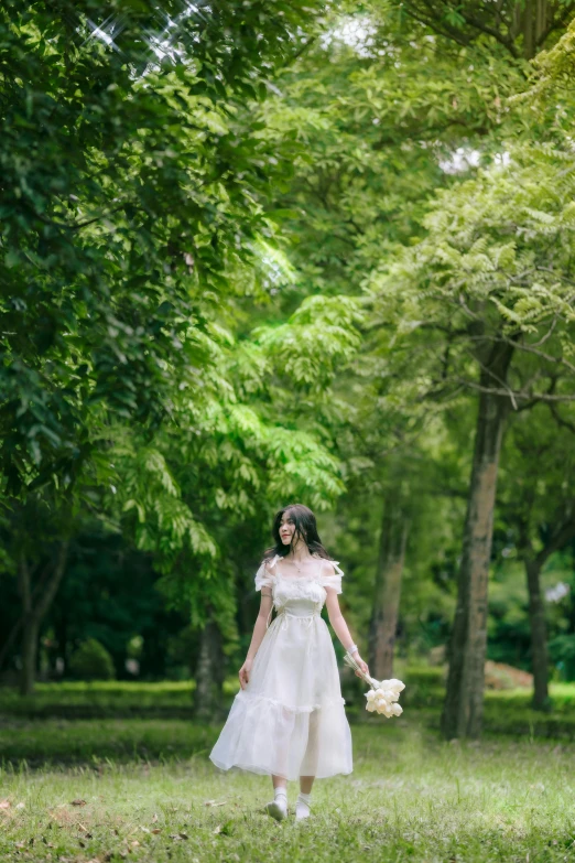 a woman in a white dress and flowers is walking through the park