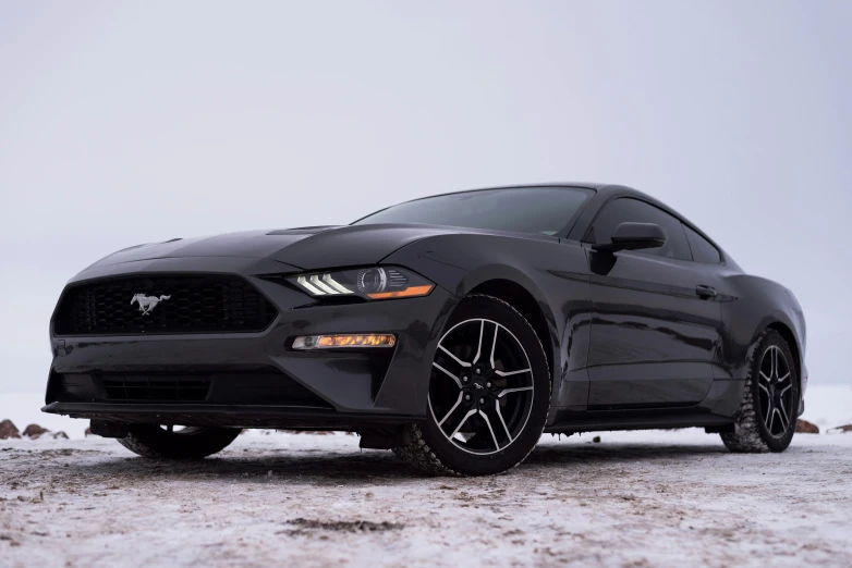 black mustang car with its wheels and tire on a snowy day