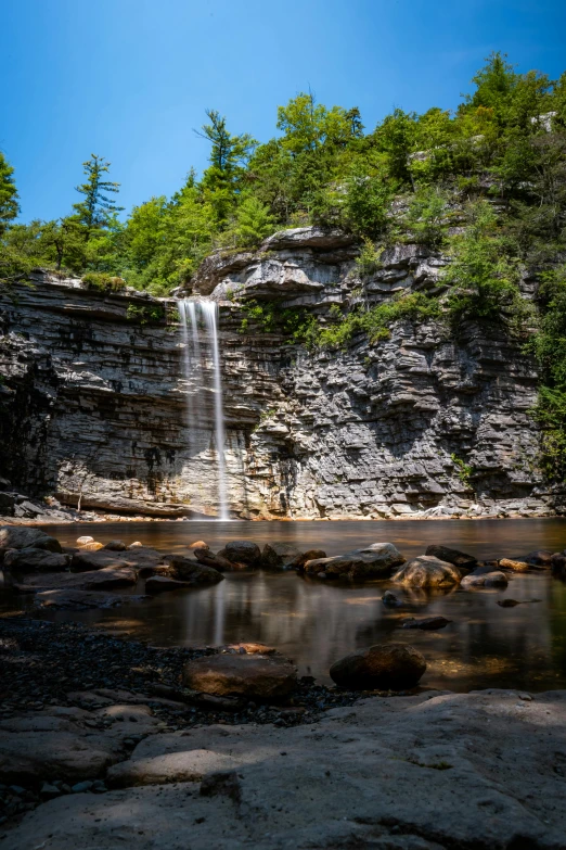 a small waterfall running into some water with lots of trees around it